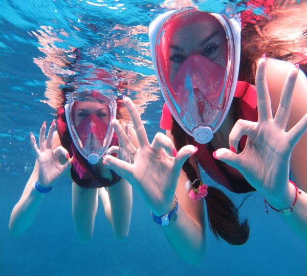 Two snorkelers enjoying an underwater adventure and giving the OK sign in the crystal-clear waters of the Red Sea."